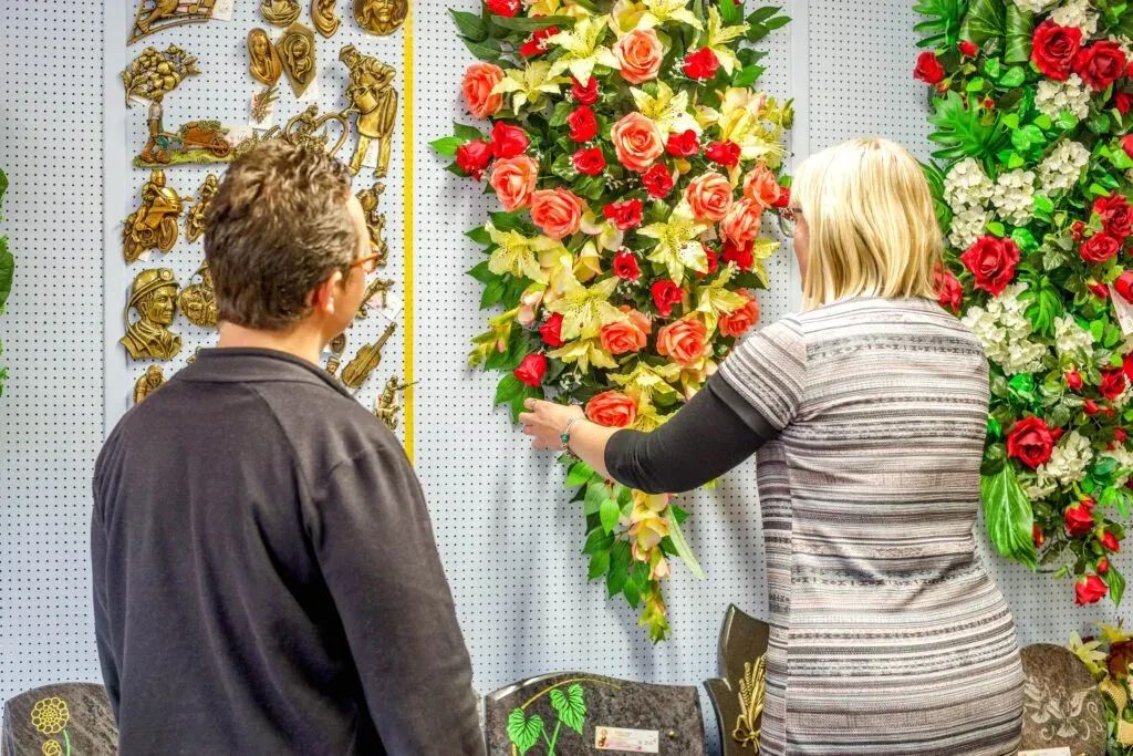 Une conseillère en pompes funèbres aide un client à choisir des fleurs.