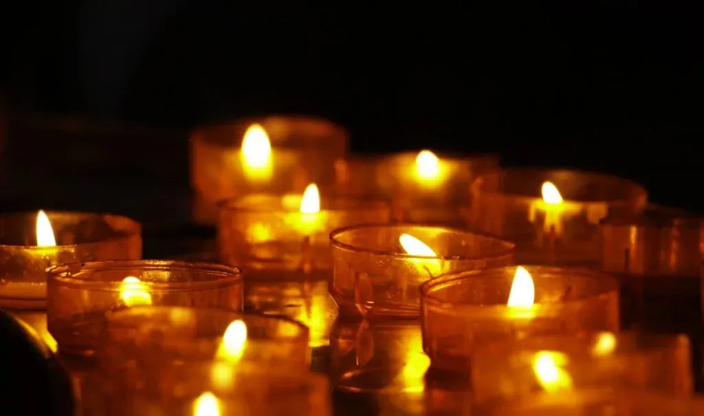 Bougies de deuil et veilleuses allumées dans l'obscurité pour se recueillir.